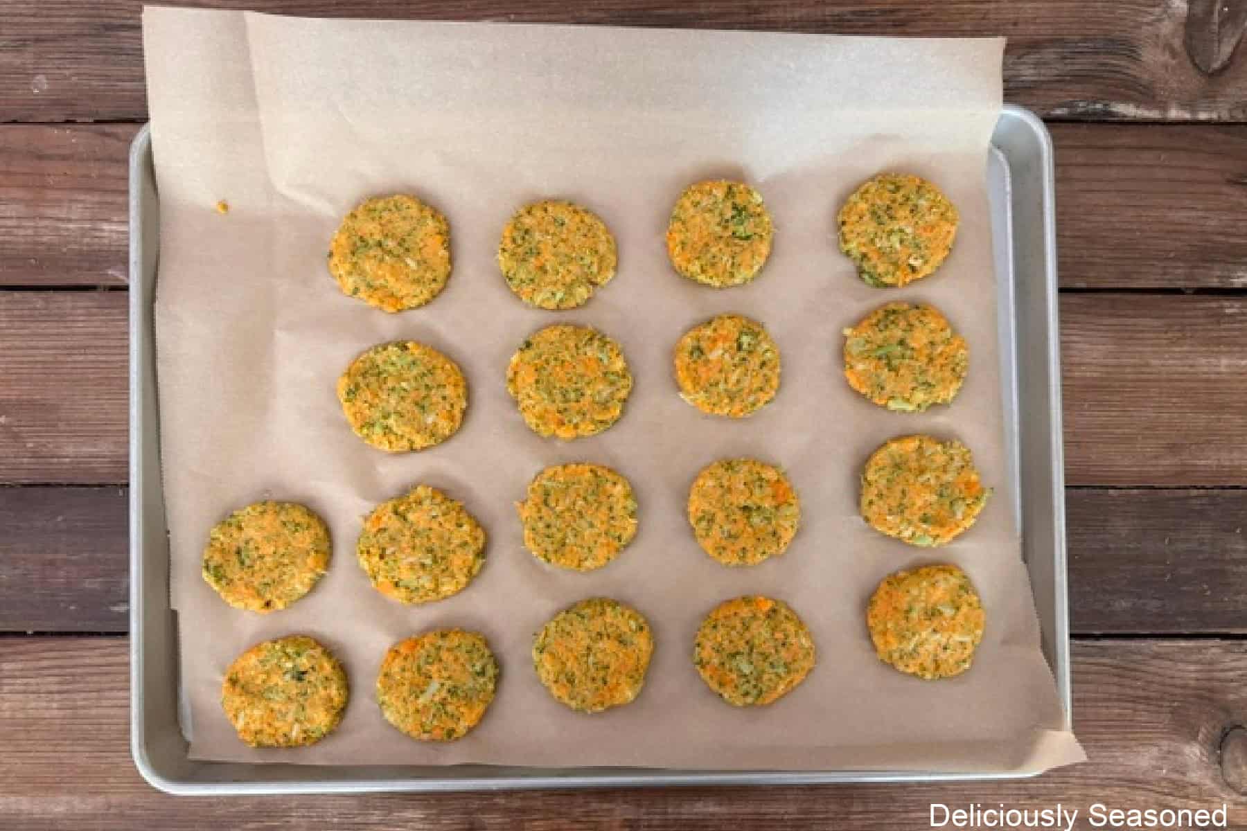 A baking sheet with sweet potato broccoli cheddar fritter patties on it before being fried.