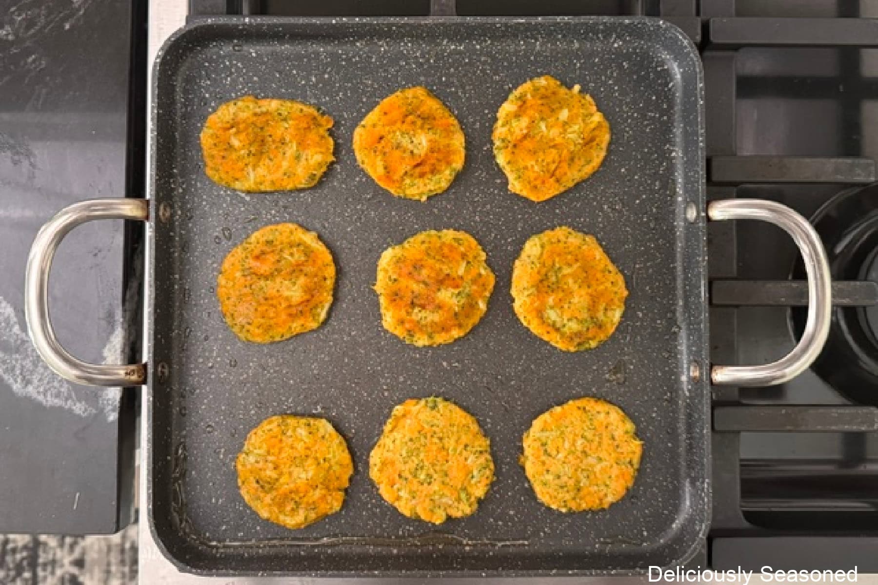 A square frying pan with nine sweet potato broccoli cheddar fritter patties being fried.