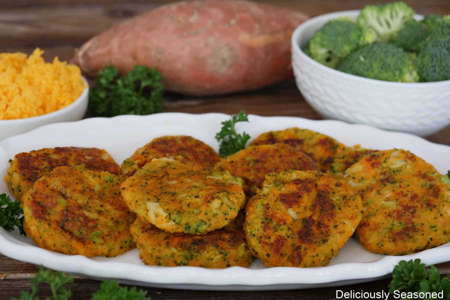 A white oval plate with ten sweet potato broccoli cheddar fritters on it.