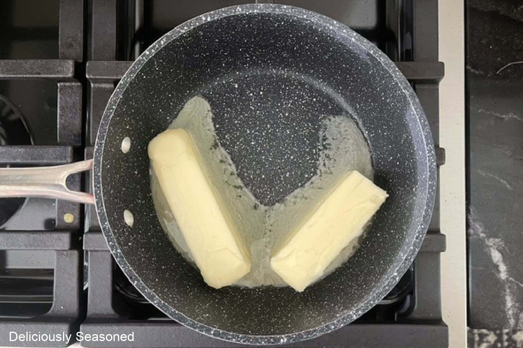 A saucepan with two sticks of butter in it melting.