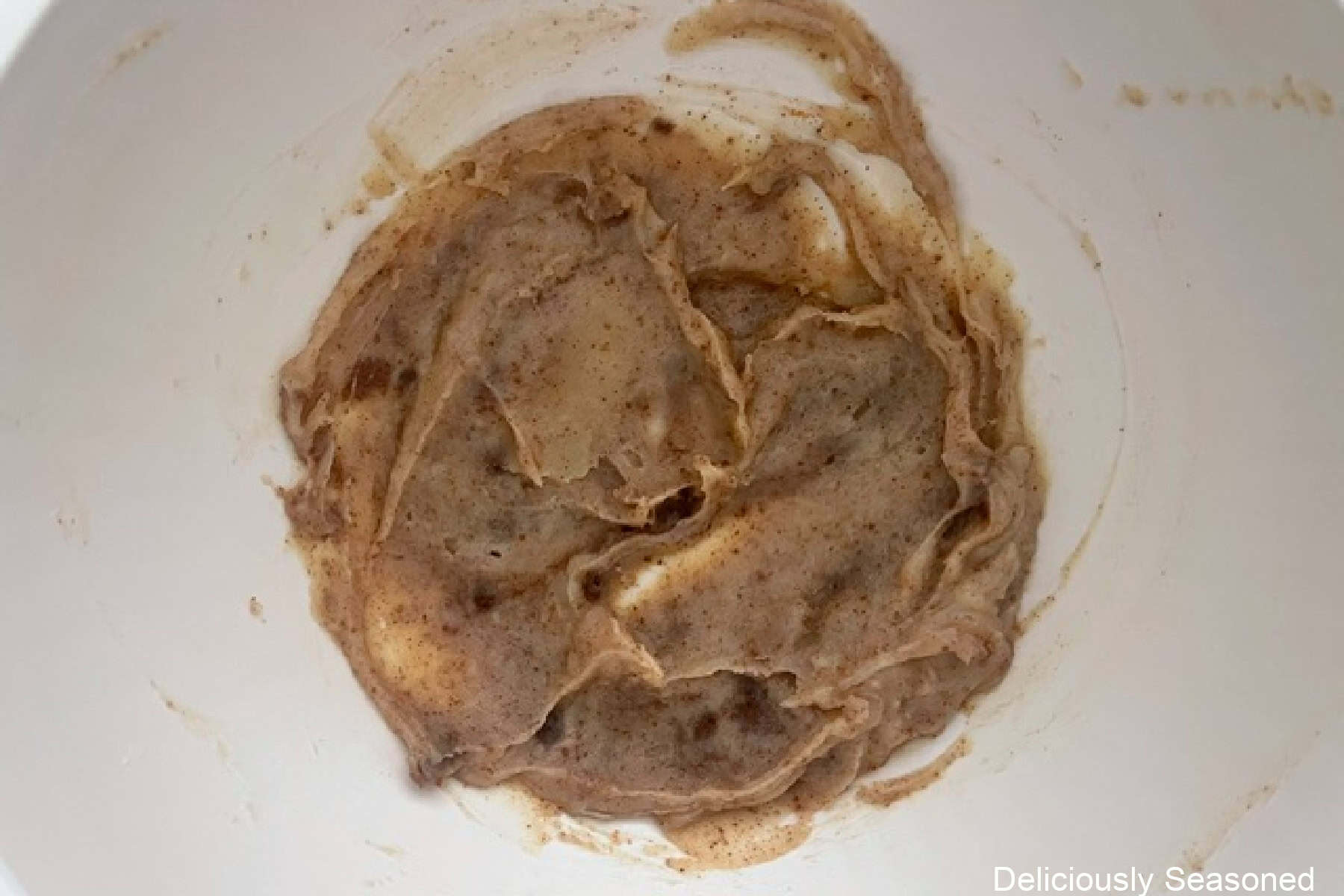 A white mixing bowl with chilled brown butter in it.