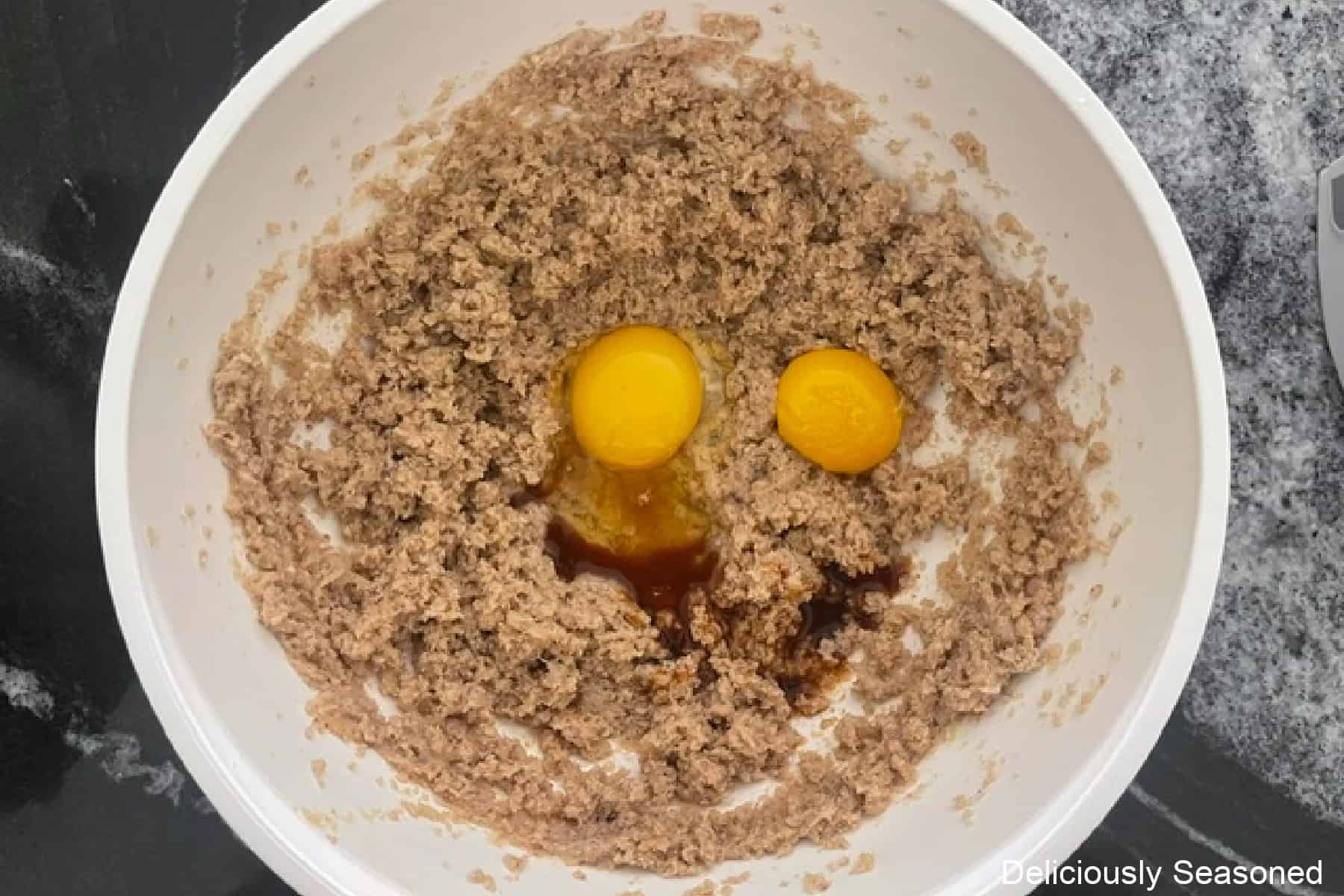 A white mixing bowl with the brown butter wet ingredients in it before being combined completely.