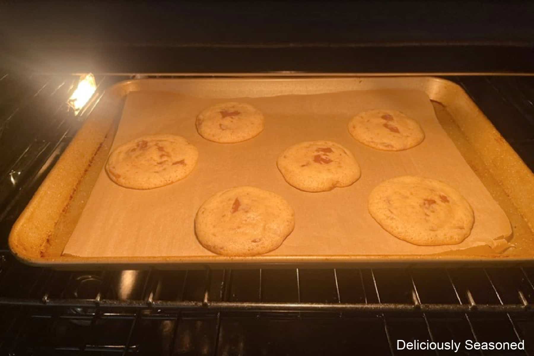 A baking sheet with cookies on it baking in the oven.