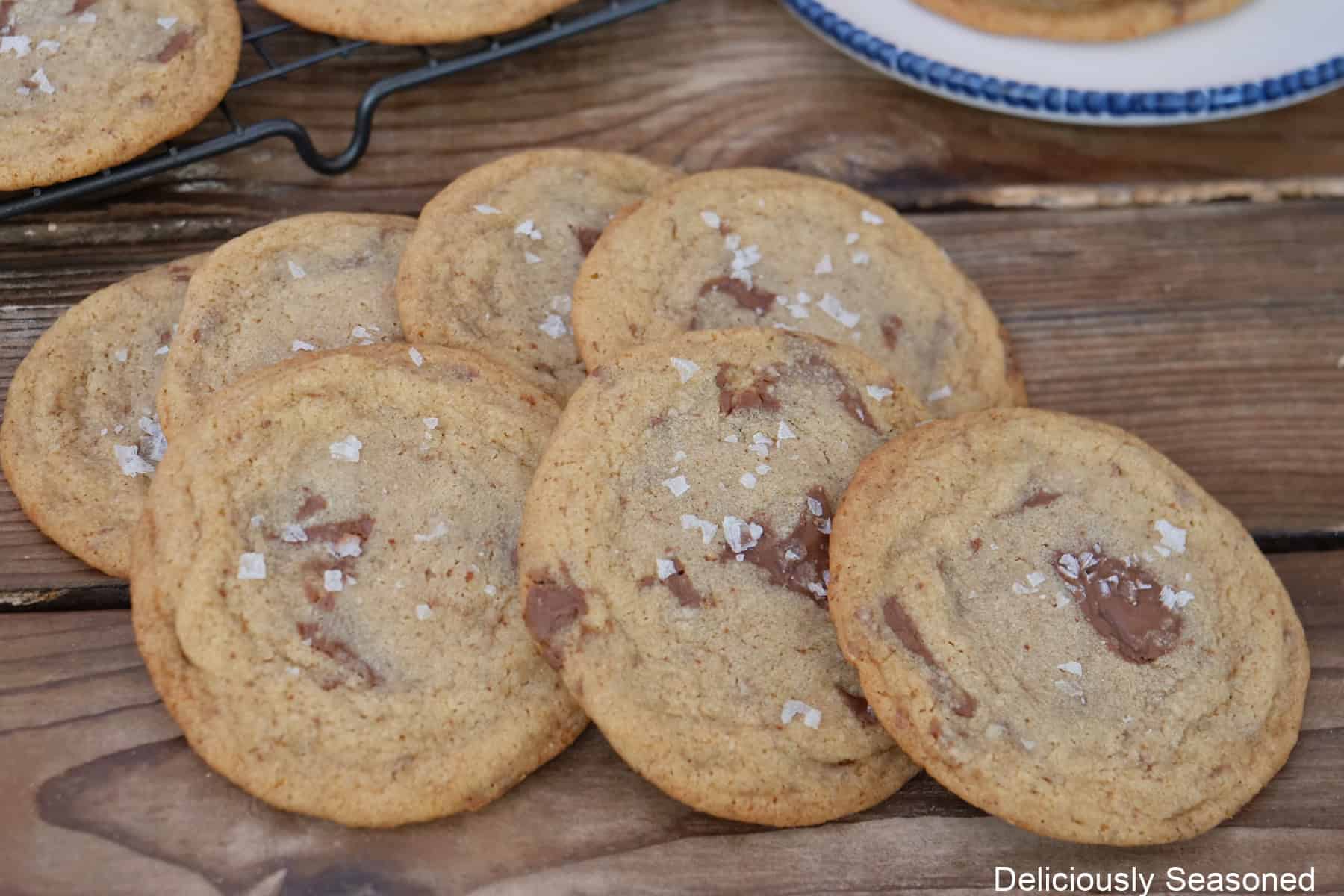 A wood surface with seven cookies on it, with more in the background.