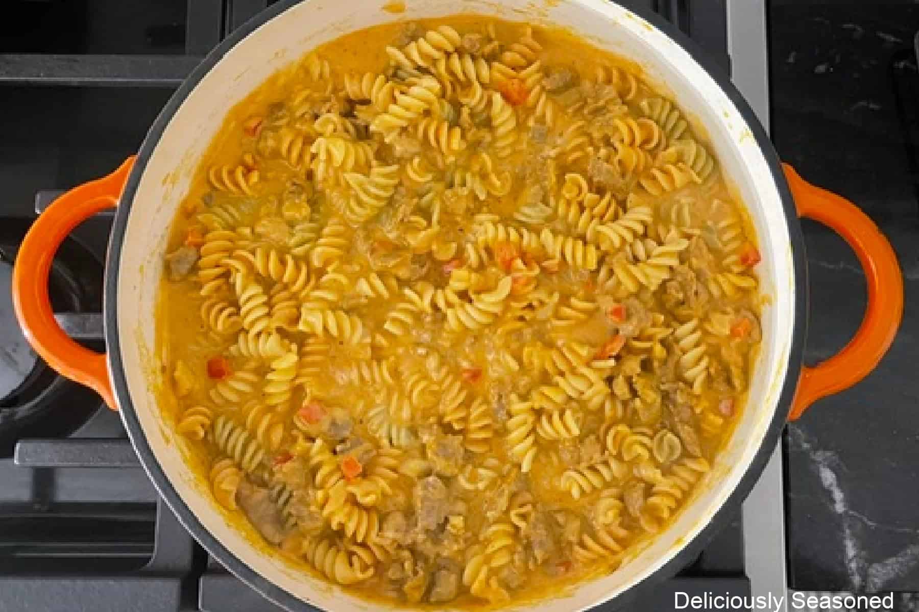 Rotini pasta added to the pumpkin sausage creamy sauce all in a cast iron pan.