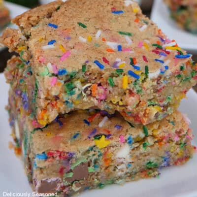 Two funfetti blondies on a white plate with a bite taken out of the blondie on top.