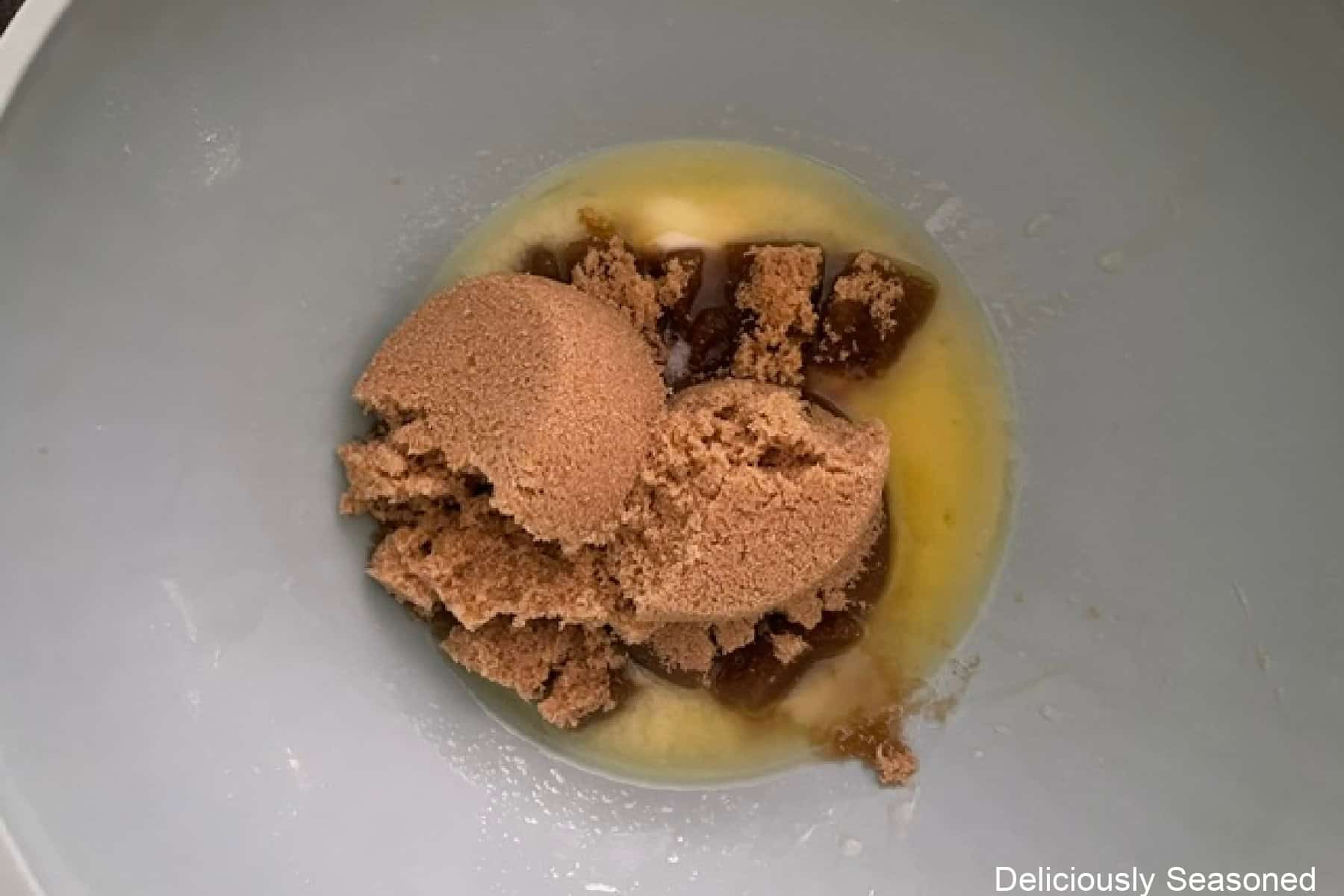 A mixing bowl with melted butter and brown sugar in it before being stirred together.