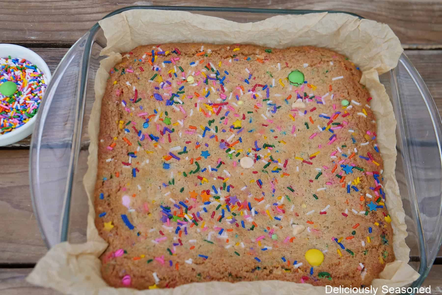 An 8 by 8 glass baking dish with baked funfetti blondies in it before being cut into servings.
