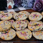 A dozen Halloween sugar cookies on a wire rack stacked on top of each other.
