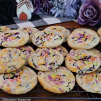 A dozen Halloween sugar cookies on a wire rack stacked on top of each other.