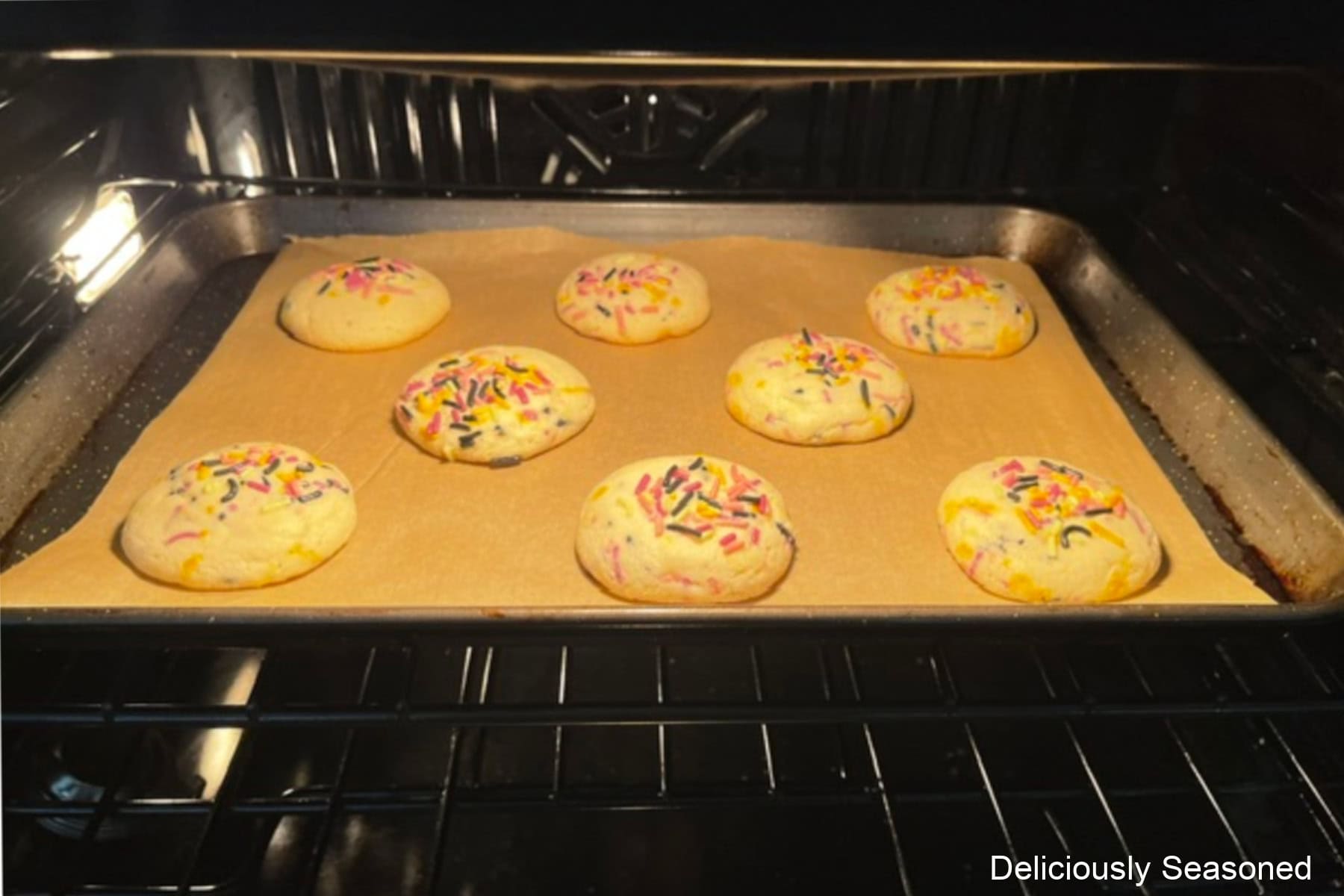 A baking sheet with Halloween sugar cookies on it baking in the oven.