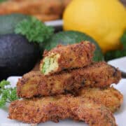 A white plate with a stack of deep fried lemon pepper avocado fries on it.