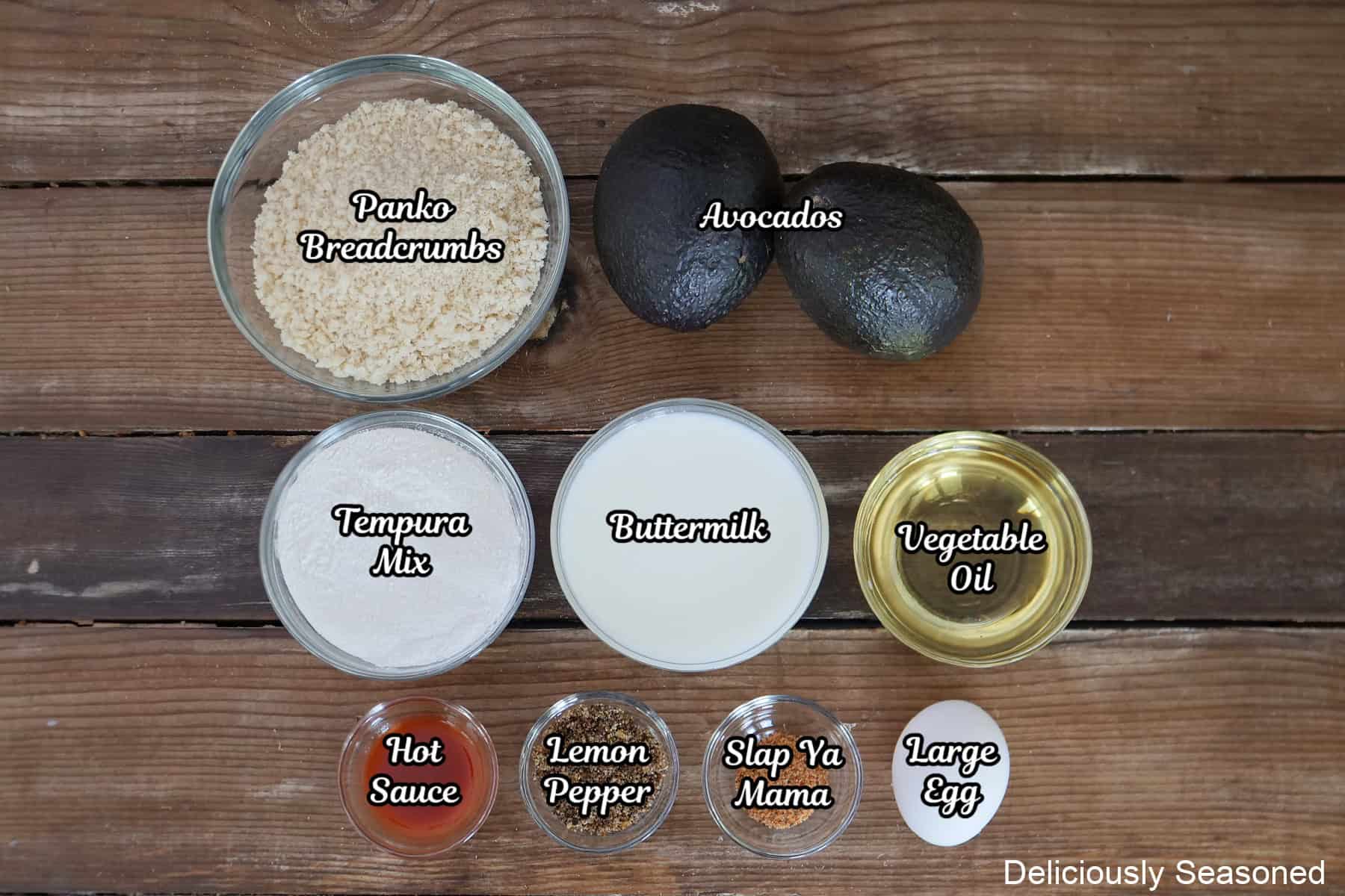 A rustic wood surface with all the ingredients placed on it to make lemon pepper avocado fries.