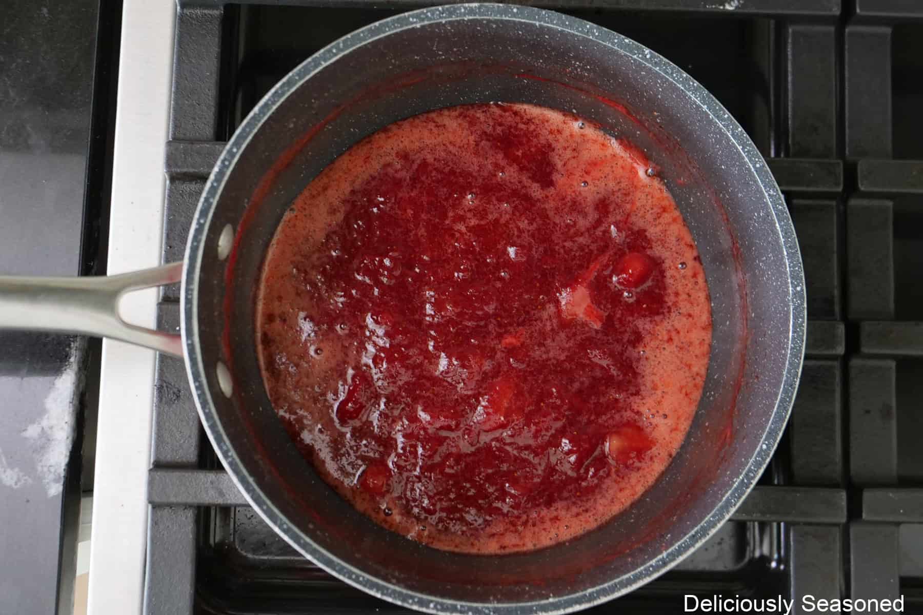 A saucepan with fresh strawberry filling being cooked.