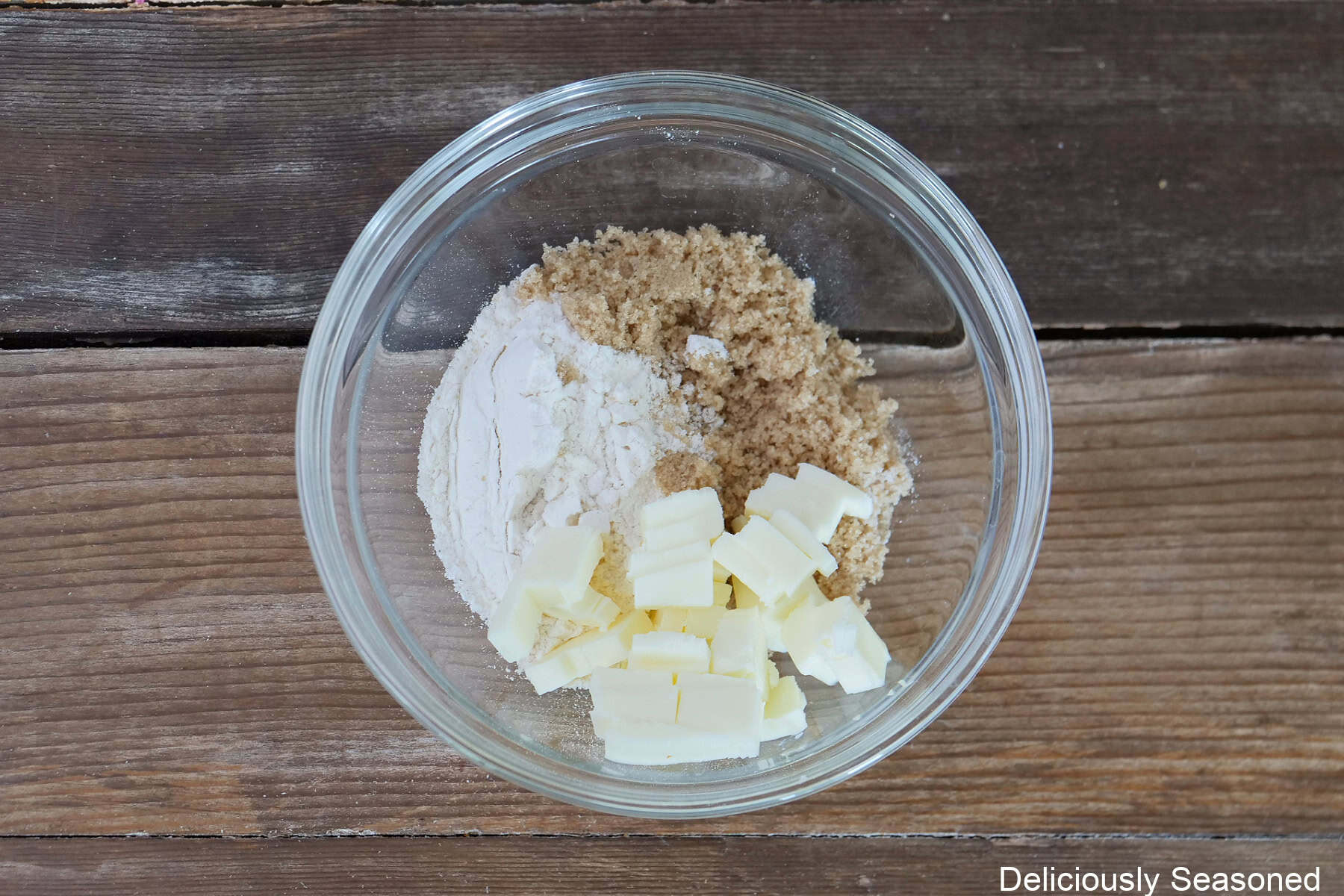 A glass bowl with the crumble ingredients in it to make the crumble for the mini strawberry cheesecake croissants.
