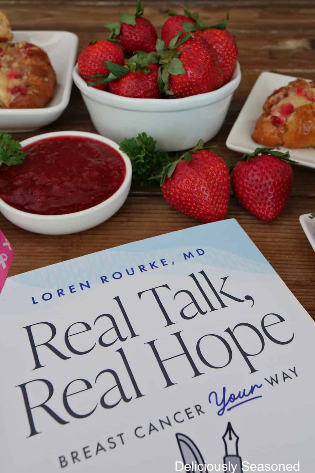 A copy of Dr. Loren Rourke's Real Talk, Real Hope with fresh strawberries and strawberry filling in the background.