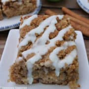 A white square plate with a serving of apple cider coffee cake on it.