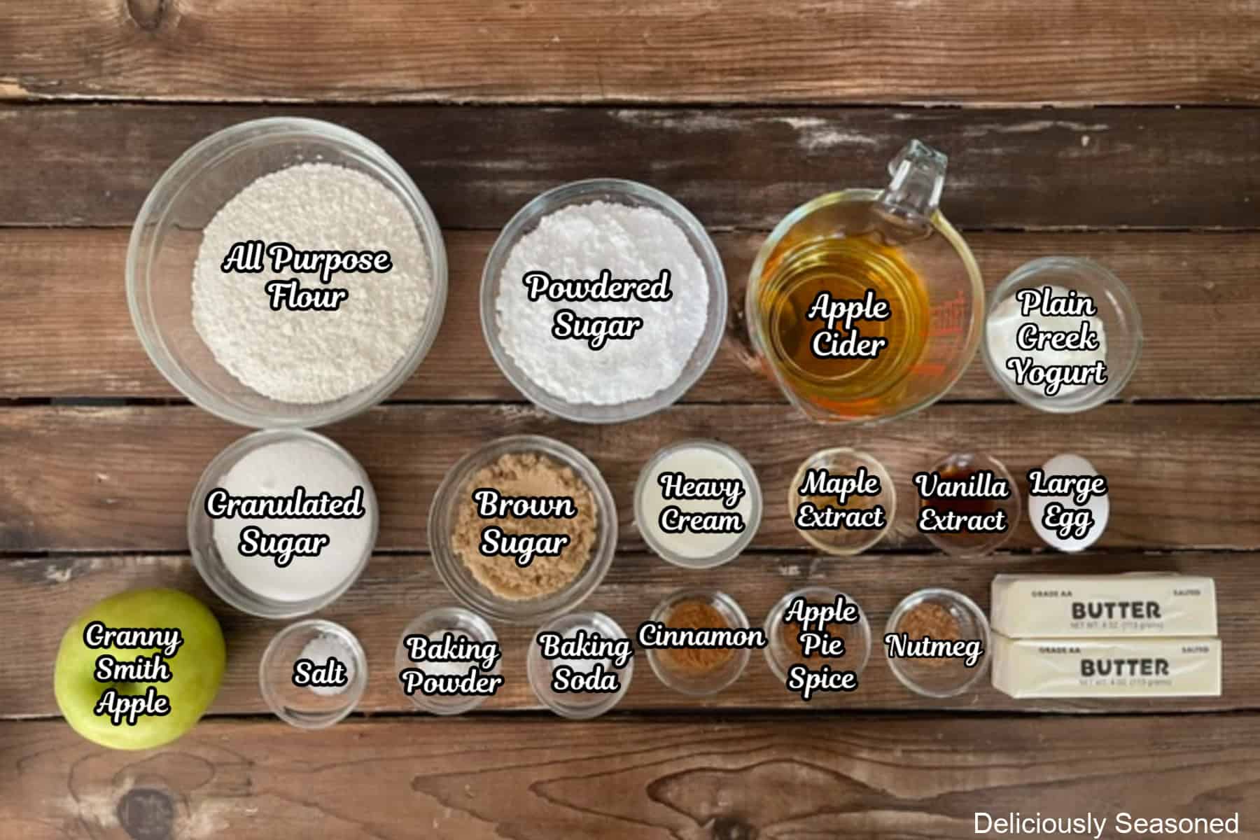 An ingredient shot with all the ingredients placed on a rustic wood surface to make apple cider coffee cake with maple icing.
