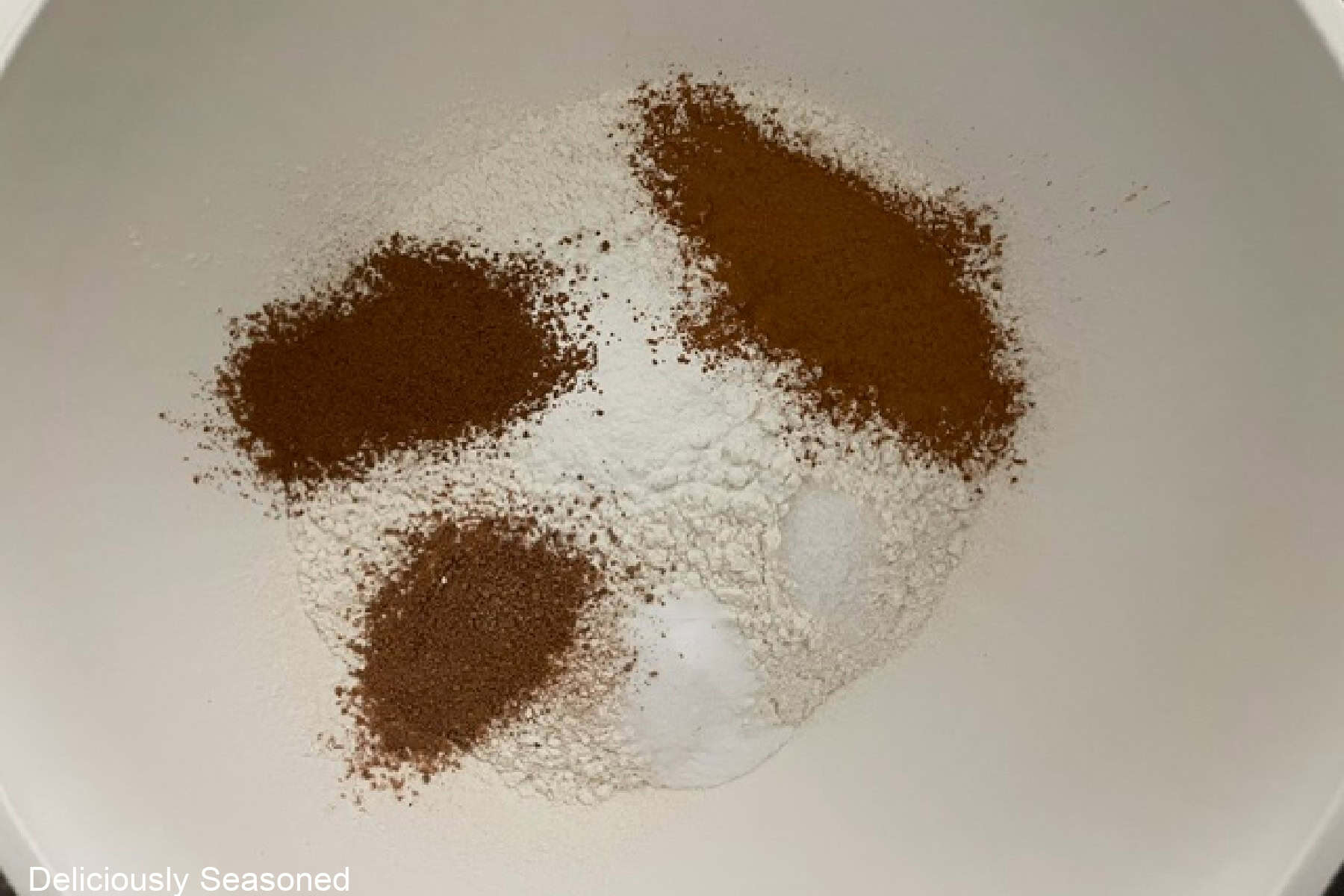 A small bowl filled with the dry apple cider coffee cake ingredients in it.