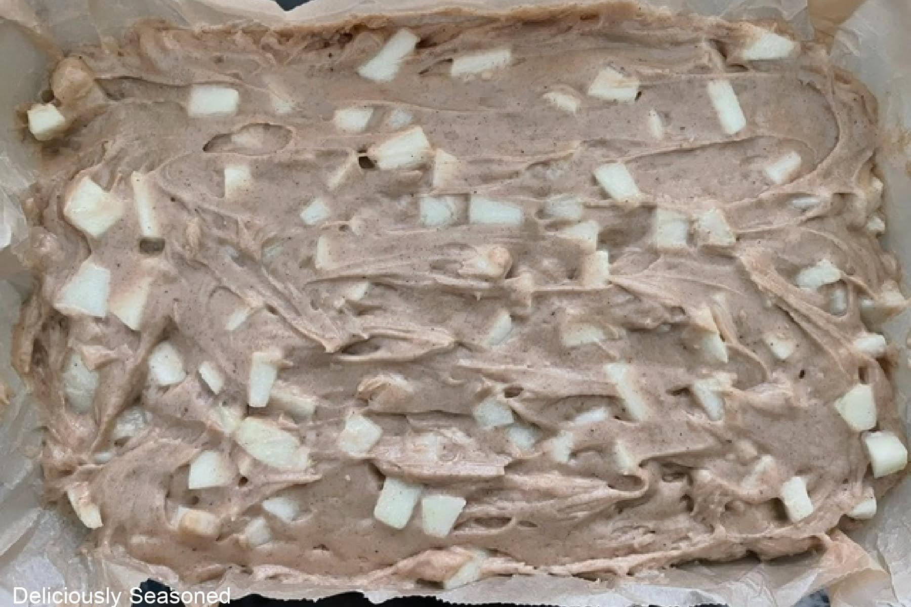 A glass baking dish with apple cider coffee cake batter in it before being baked.