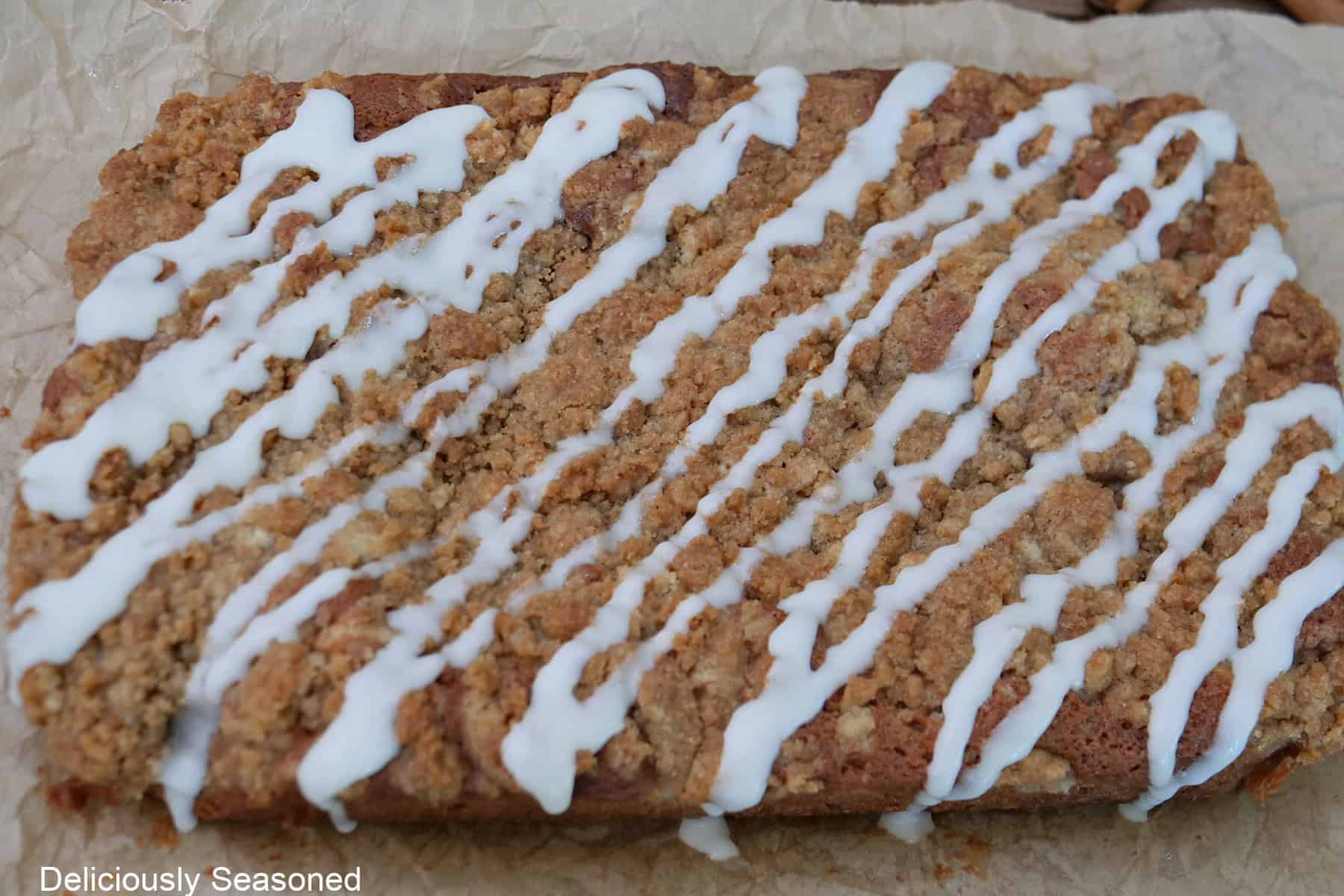 Maple icing drizzled over a baked apple cider coffee cake.