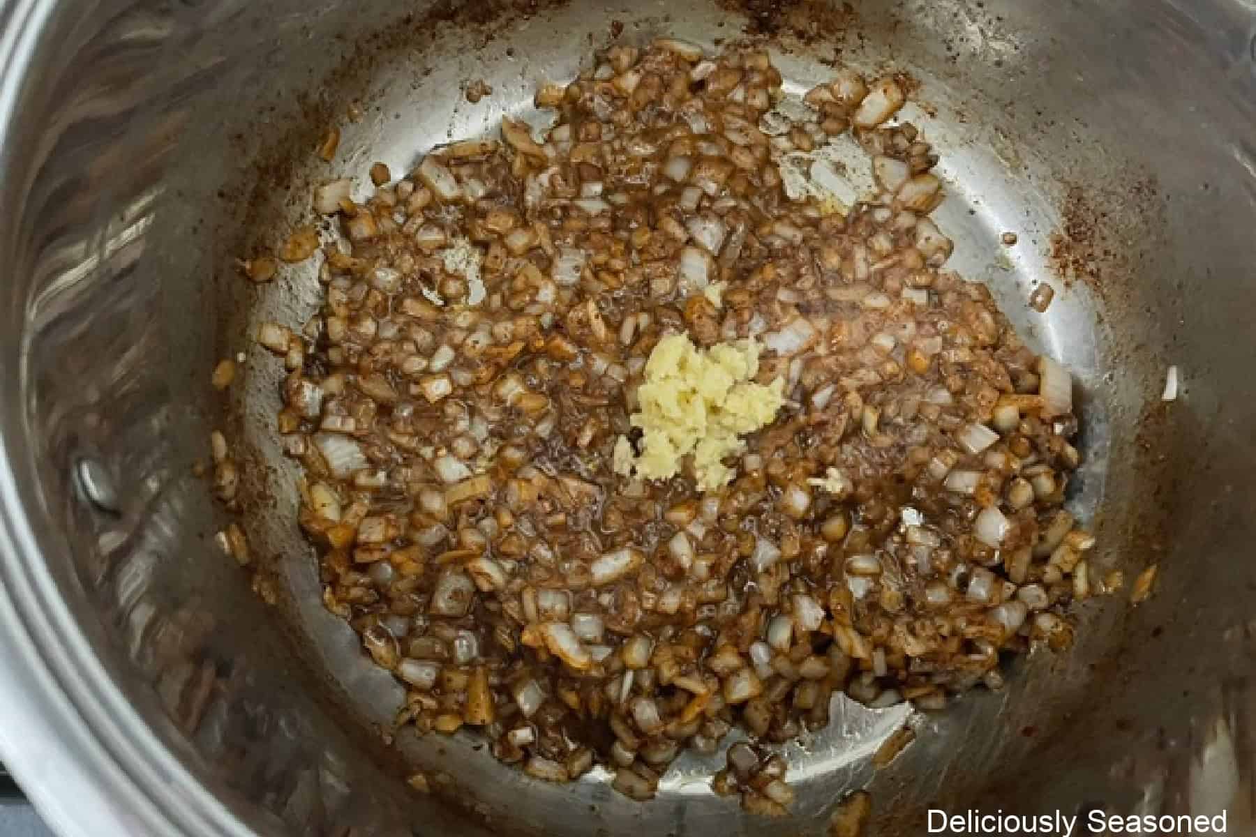 A pot with sauteed onions and minced garlic added.