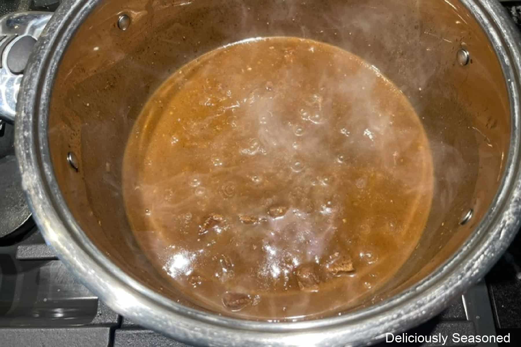 A pot of beef gravy and beef simmering.