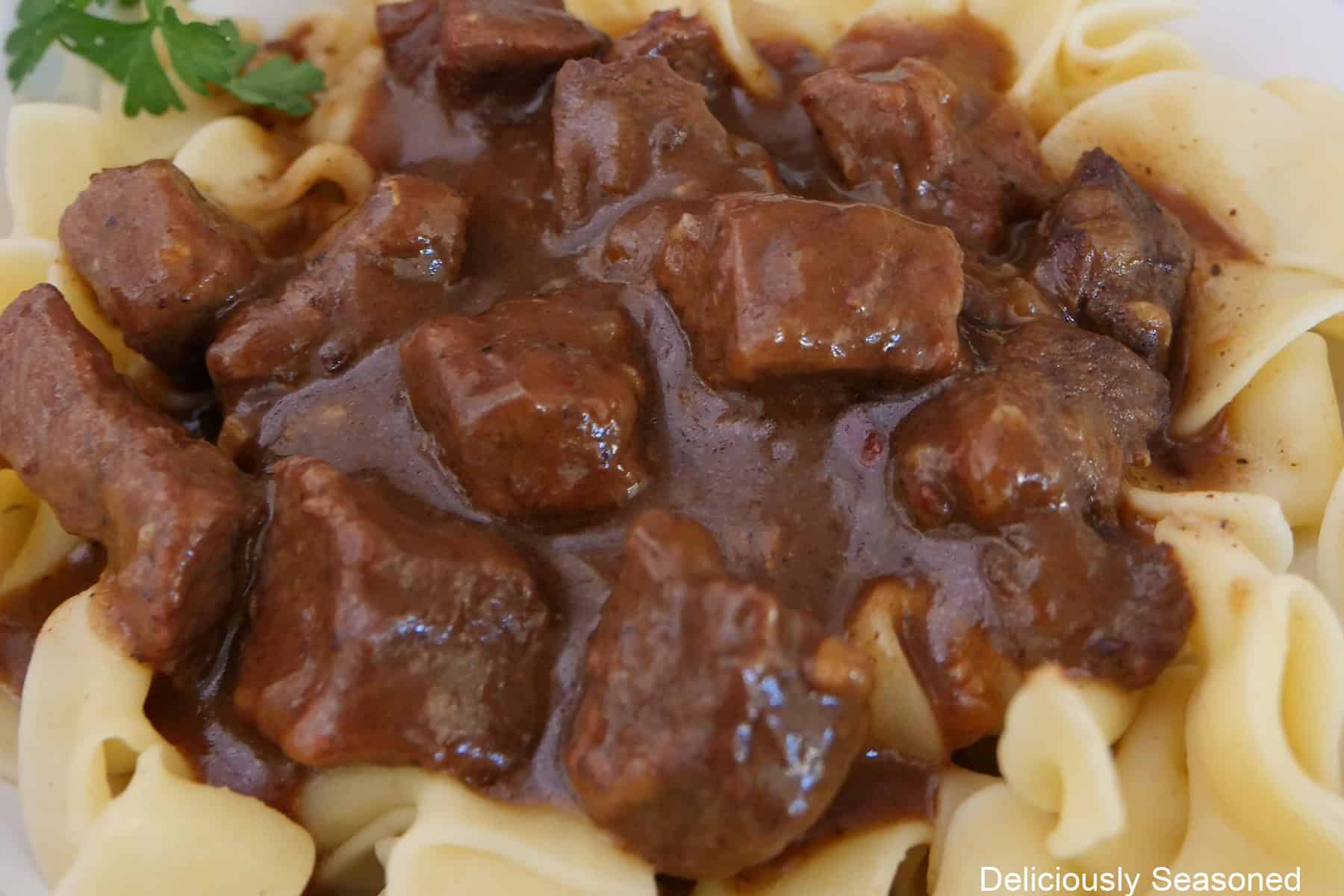 A bowl of egg noodles with beef and gravy on top.