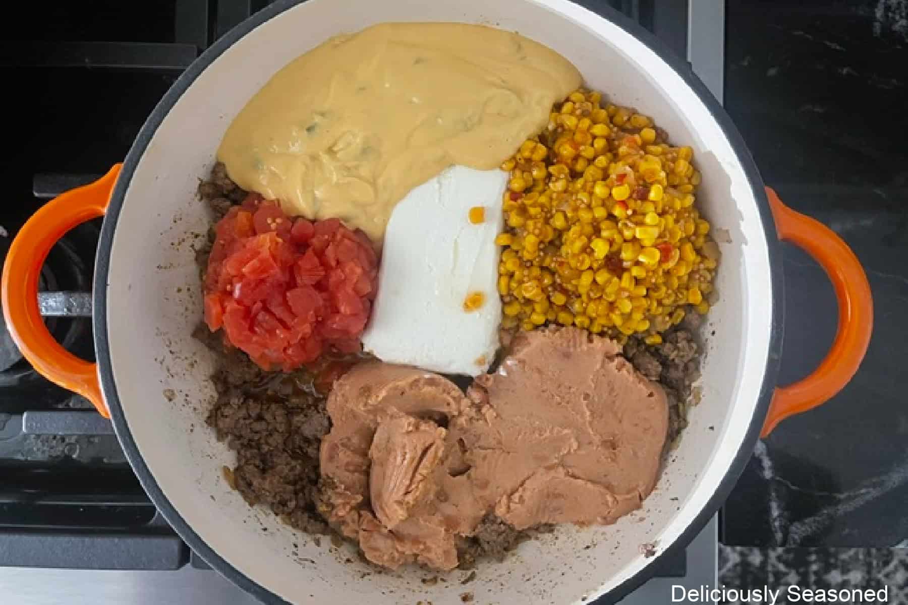 A pan with all the ingredients in it to make cheesy queso taco dip except the shredded cheese and fritos.