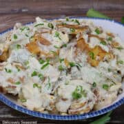 A white bowl with blue trim filled with a serving of crispy potato salad.