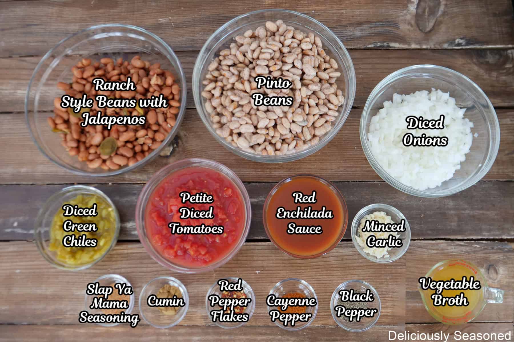 A rustic wood surface with all the ingredients to make crock pot spicy beans placed on it.