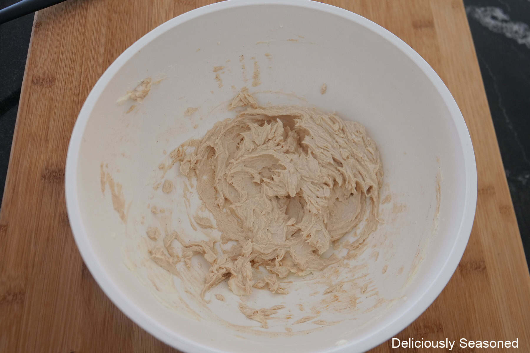 A white bowl filled with a cream cheese molasses frosting in it.