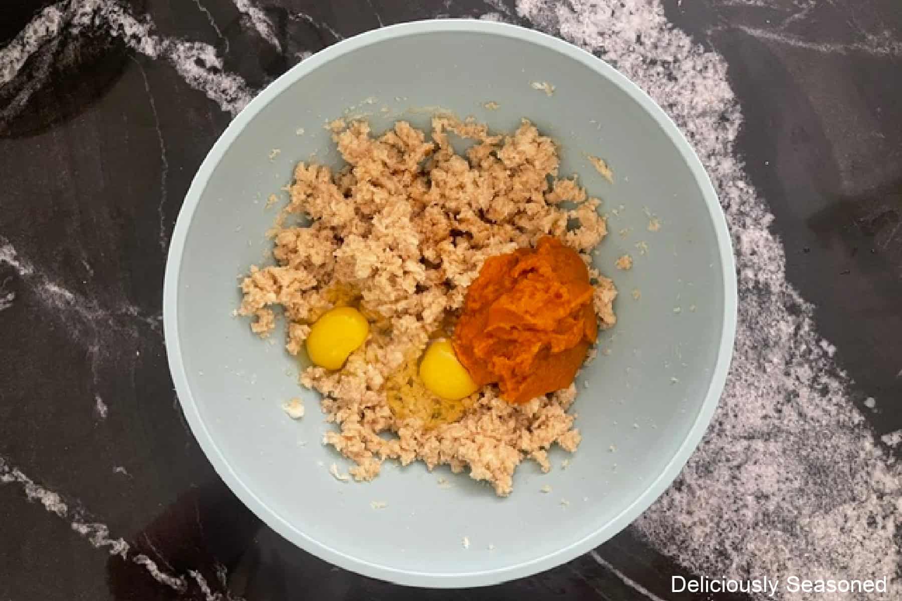 A light blue mixing bowl with the wet batter pumpkin cookie ingredients in it before being combined.