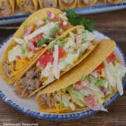 A white plate with blue trim with three pork tacos on it.