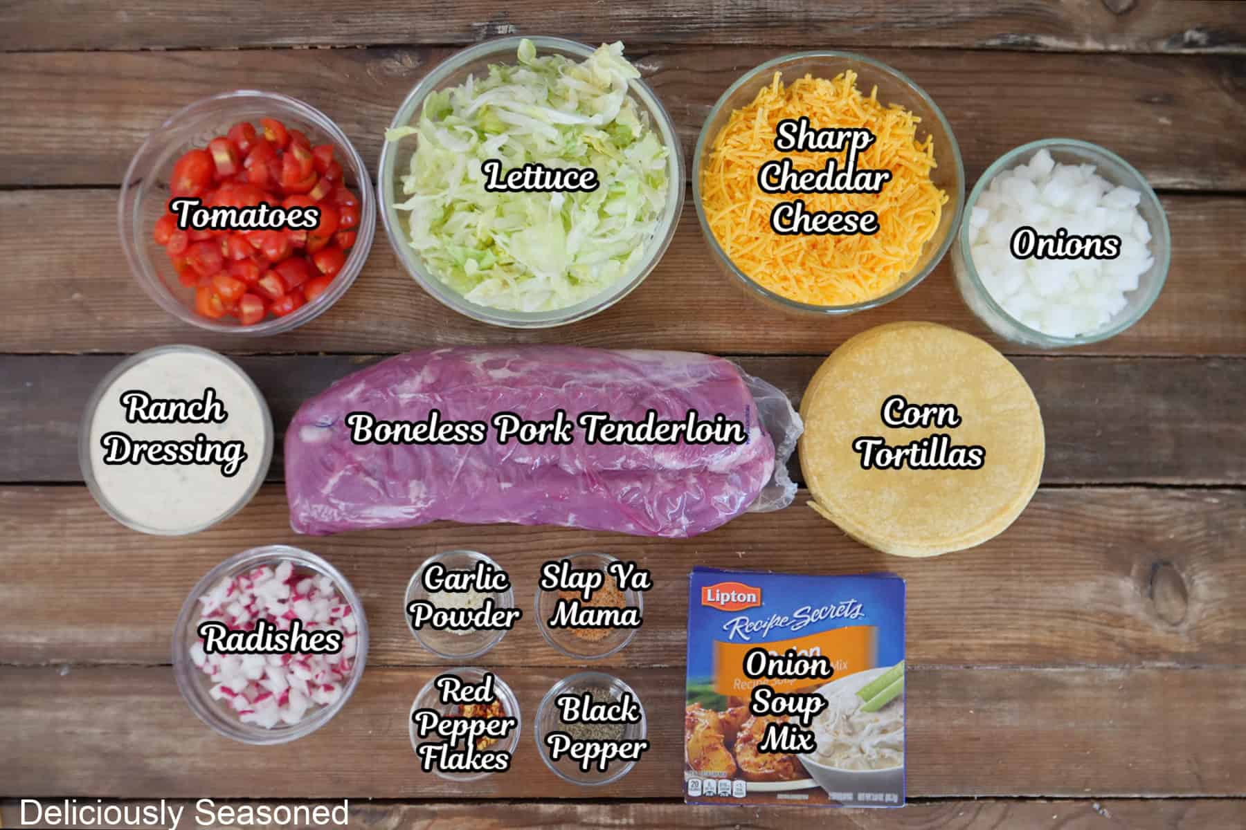 A rustic wood surface with all the ingredients placed on it to make crock pot pork tacos.