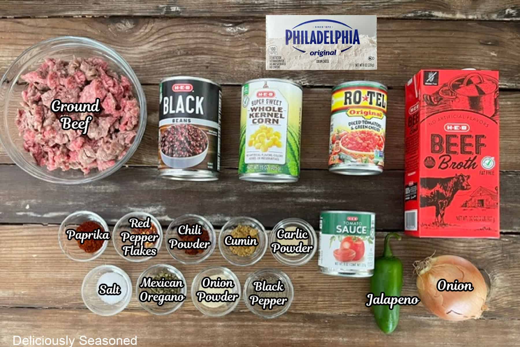 A rustic wood surface with all the ingredients to make Southwest taco soup are placed on it.