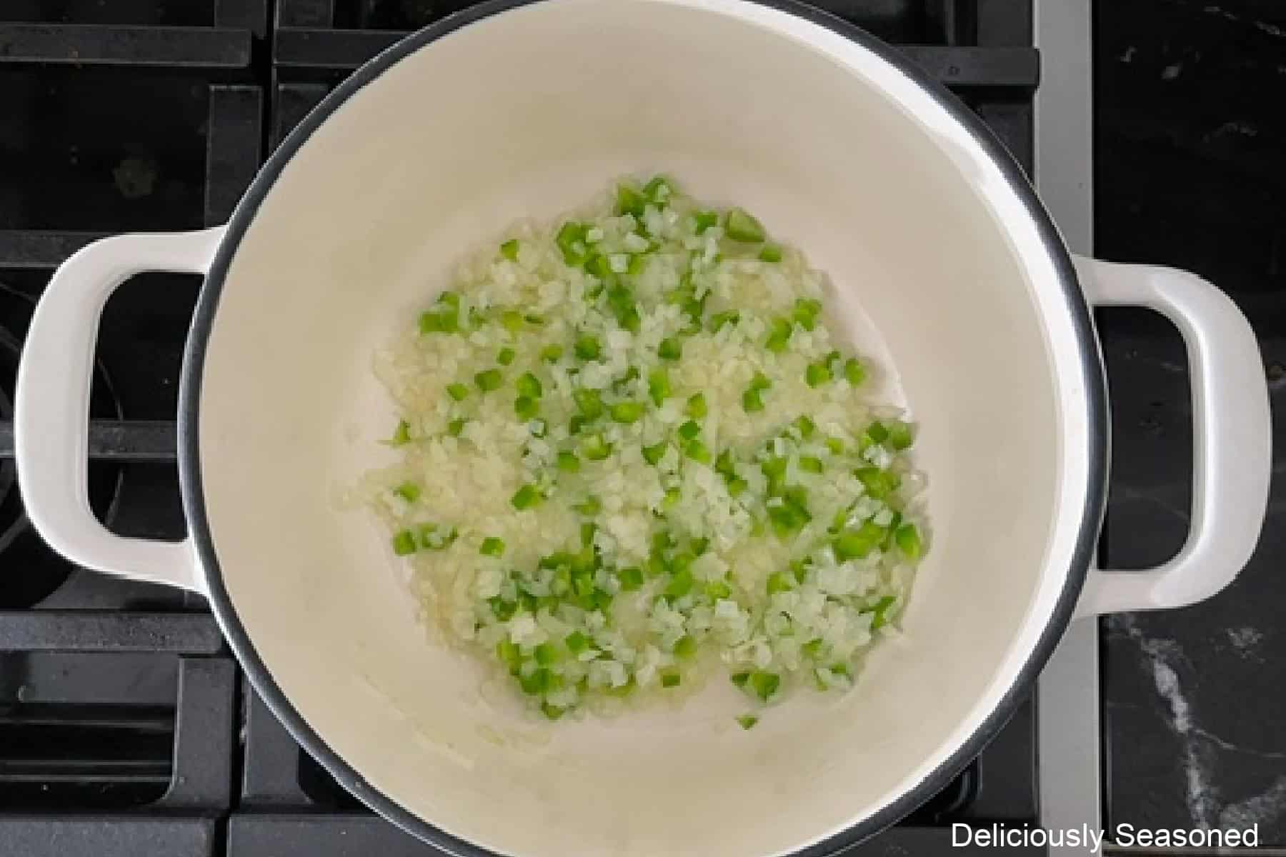 A cast-iron skillet with sauteed onions and jalapenos in it.